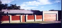 A long shot of the front door, garage door and fence combination of the place pictured left